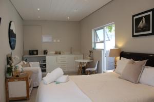 a bedroom with a large bed and a kitchen at Sea Breeze Cottage in Cape Town
