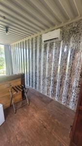 a room with a wall with curtains and a chair at Hospedagem Pé de Serra in Botucatu