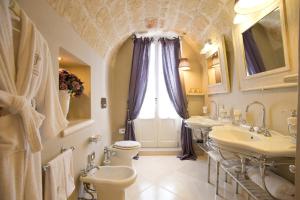 a bathroom with two sinks and a toilet and a window at Hotel Don Ferrante in Monopoli