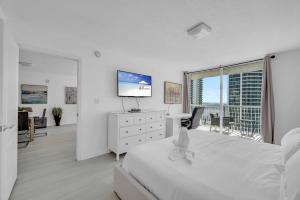 een witte slaapkamer met een groot bed en een televisie bij Deluxe 1 Bedroom Apartment • Brickell • Ocean View in Miami