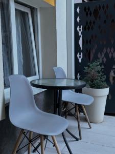 uma mesa preta e duas cadeiras brancas numa varanda em Vila Storia em Niš