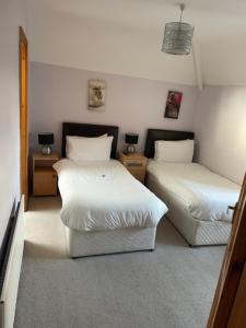 una camera con due letti e due comodini di Padua Guest Accommodation Rosslare a Rosslare