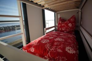 Cama roja en una habitación pequeña con ventana en Modernes festliegendes Hausboot mit großzügiger Dachterrasse und Ruderboot, en Röbel