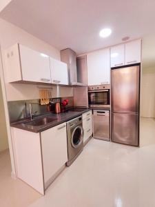 a kitchen with white cabinets and a stainless steel refrigerator at Умные новые аппартаменты в Торревьехе in Torrevieja