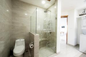 a bathroom with a toilet and a glass shower at Lake Arenal Condos in Naranjos Agrios