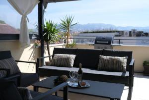een patio met een bank en een tafel met wijnglazen bij Prime Location Penthouse apt with a large terrace in Split