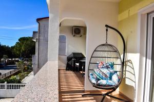 a swinging chair on a porch with a table at Apartmani Čeko in Selce