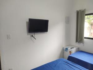 1 dormitorio con TV de pantalla plana en la pared en Casa Cardoso en Bertioga