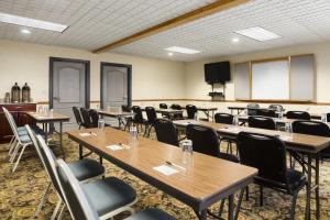 Country Inn & Suites by Radisson, Columbus West, OH في كولومبوس: قاعة اجتماعات مع طاولات وكراسي وتلفزيون