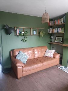 a brown leather couch in a living room with book shelves at Guildford Road Cottage in Ash