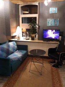 sala de estar con sofá, mesa y TV en Chimay Welcome, en Chimay