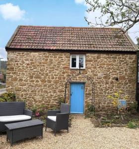 a brick building with a blue door and two chairs at The Barn in Cam