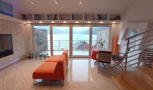 een woonkamer met een oranje bank en een tafel en stoelen bij Sea View Apartment Ljuta in Kotor