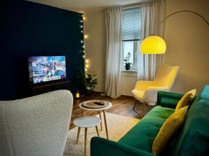 # One Apartment's / Parkplatz / Schlossplatz في كوبورغ: غرفة معيشة مع أريكة خضراء وتلفزيون
