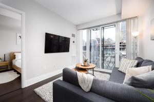 uma sala de estar com um sofá e uma televisão em DWTN Condo Near CN Tower! w/ Free Parking em Toronto