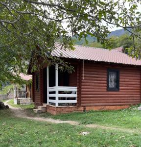 eine kleine Blockhütte mit einer Veranda und einem Fenster in der Unterkunft Thethi Paradise Hotel & Restaurant in Theth
