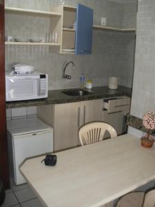 una pequeña cocina con microondas y mesa en Flat Mobiliado, en João Pessoa