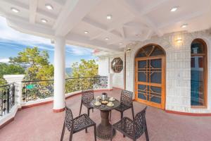 um pátio com cadeiras e uma mesa na varanda em Calm Cottage KASAULI HILLS Barog em Barog mais 5 fotografias