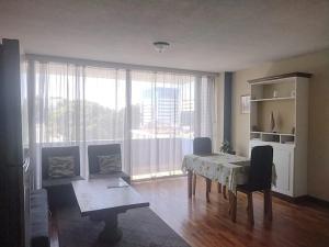a living room with a table and a large window at Apartamento 505 Cortijo Reforma zona 9 in Guatemala
