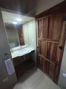 uma casa de banho com um lavatório e uma porta de madeira em El Aromo em Cafayate