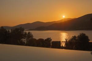 a sunset over a body of water with mountains at Villa Armiriki-Private Sea Access in Évyiros