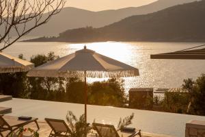 een patio met een parasol en stoelen naast een meer bij Villa Armiriki-Private Sea Access in Évyiros