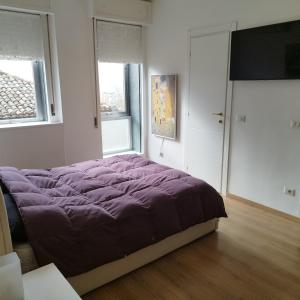 1 Schlafzimmer mit einem lila Bett und 2 Fenstern in der Unterkunft Garibaldi Guest House in Macerata