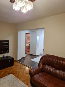 ein Wohnzimmer mit einem Ledersofa und einem Kronleuchter in der Unterkunft Luxury Large Family Apartment in Zalău