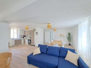 a living room with a blue couch and a kitchen at Moscow, Maison spacieuse proche Reims in Berru
