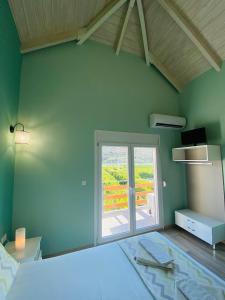 a green room with a large window and a bed at Ktima Klimentini in Vivari