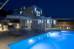 a villa with a swimming pool at night at Villa Armiriki-Private Sea Access in Évyiros