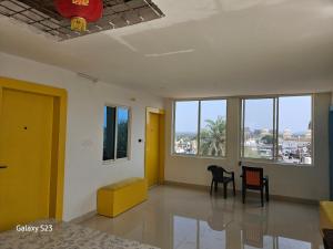 a room with a yellow door and chairs and windows at The Ortus Stays -The Sunset Room in Orchha