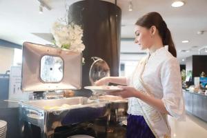 a woman standing in a kitchen holding a plate at Wangchan Riverview in Phitsanulok