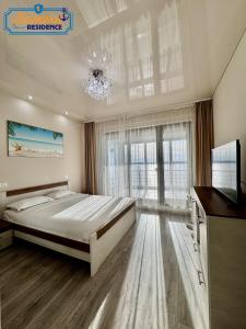 a bedroom with a bed and a television and a chandelier at Lamera Residence Mamaia - Apartamente cu 1-2-3 camere cu acces si vedere la lac in Mamaia