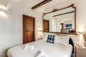 a bedroom with a white bed and a mirror at MAYA RHOME TRASTEVERE in Rome