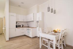 a white kitchen with a white table and chairs at Bright 73m2 Apartment - Blaumana Street Central in Riga