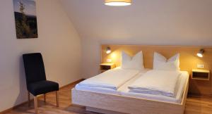 een slaapkamer met een wit bed en een zwarte stoel bij Ferienhof Fischer in Seebach