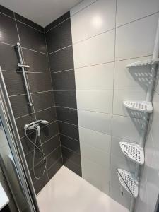 a shower with black and white tiles in a bathroom at Chalet au pied des pistes, le lioran, terrasse, 2 chambres, 4 lits in Laveissière