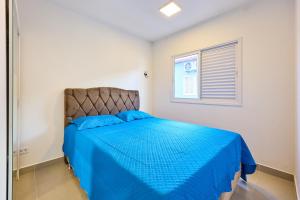 een slaapkamer met een blauw bed en een raam bij Orla Ubatuba 300 metros - Ar condicionado, Varanda Gourmet in Ubatuba