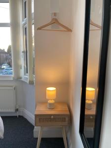 una mesa con una lámpara junto a un espejo en University View-Off-Street Parking-Sleeps 8-Fast WiFi en Nottingham