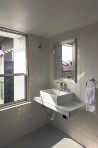 baño blanco con lavabo y ventana en Posada Galeria Alberto Sedas en Huatusco de Chicuellar