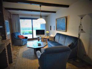 ein Wohnzimmer mit einem Sofa, Stühlen und einem TV in der Unterkunft Haus Halligblick, Ferienwohnungen am Wattenmeer, WhgHooge in Dagebüll