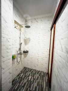 a bathroom with a shower with white brick walls at Pala House in Ubud