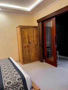 a bedroom with a bed and a wooden cabinet at Pala House in Ubud