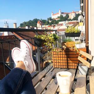 une personne assise sur un balcon avec ses pieds sur le fond dans l'établissement Apartments Bastova, Stela & Mia Apartments, à Bratislava