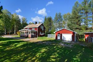czerwona stodoła z garażem obok domu w obiekcie Guestly Homes - 3BR Lakeview House w mieście Piteå