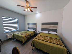 a bedroom with two beds and a ceiling fan at Texas Bungalows Hotel and Hotel Que in Pflugerville