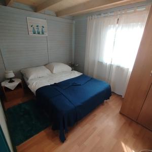 a bedroom with a bed with a blue blanket and a window at Ośrodek Azyl Mironice in Kłodawa