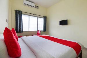 Schlafzimmer mit einem Bett mit roten Kissen und einem Fenster in der Unterkunft OYO Royal Residency in Sūramangalam