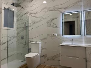 baño con aseo y pared de mármol en Valdeolivas Suites, en Valencia